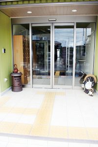 施設の玄関入口。自動ドア、掲示板、待合スペース完備